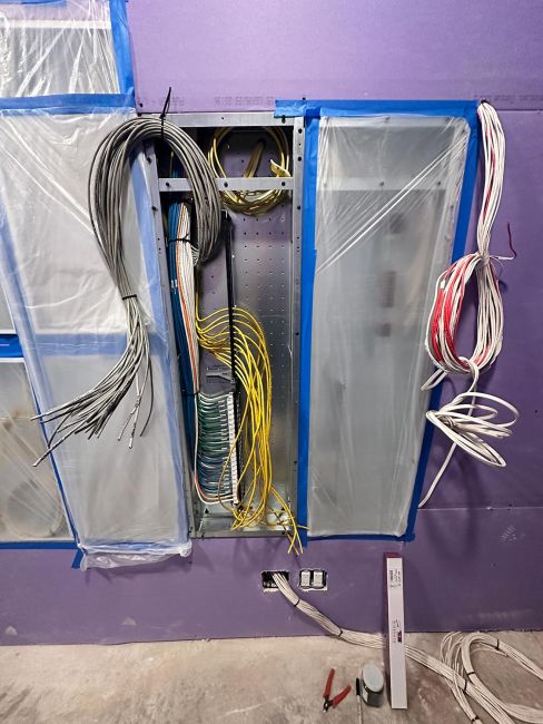 Media enclosure panel with various colored wires and cables bundled during construction