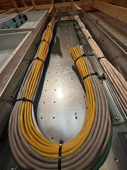 Detailed look at thick bundles of yellow and grey wires secured with cable ties in a metal tray