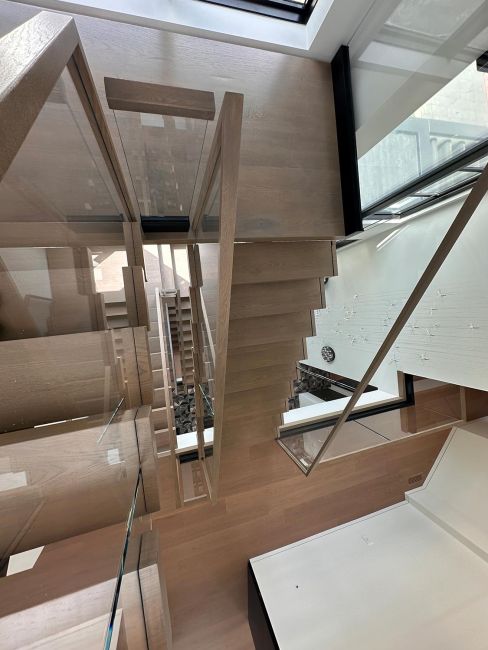 High-angle perspective looking down a multi-story open staircase with glass railings