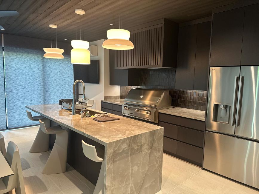 Contemporary kitchen side view showing stone counters, dark cabinets, and stainless appliance