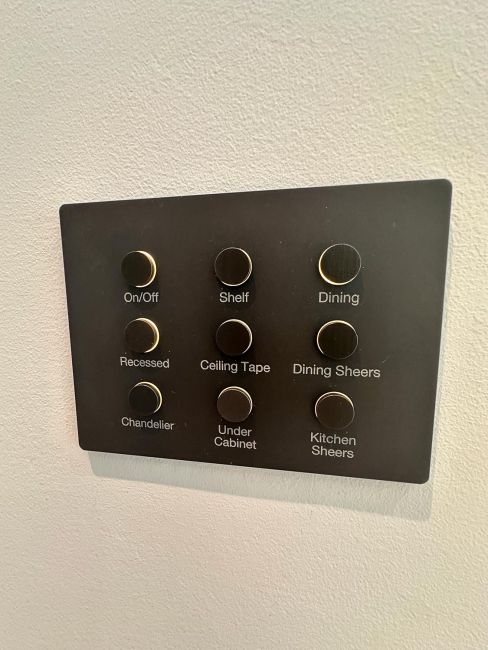 Black wall-mounted automated keypad panel with nine small circular buttons