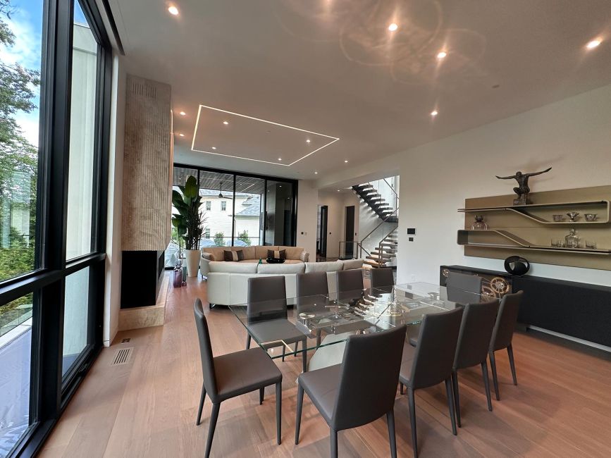 Luxury open floor plan dining area with long glass table and dark gray modern chairs