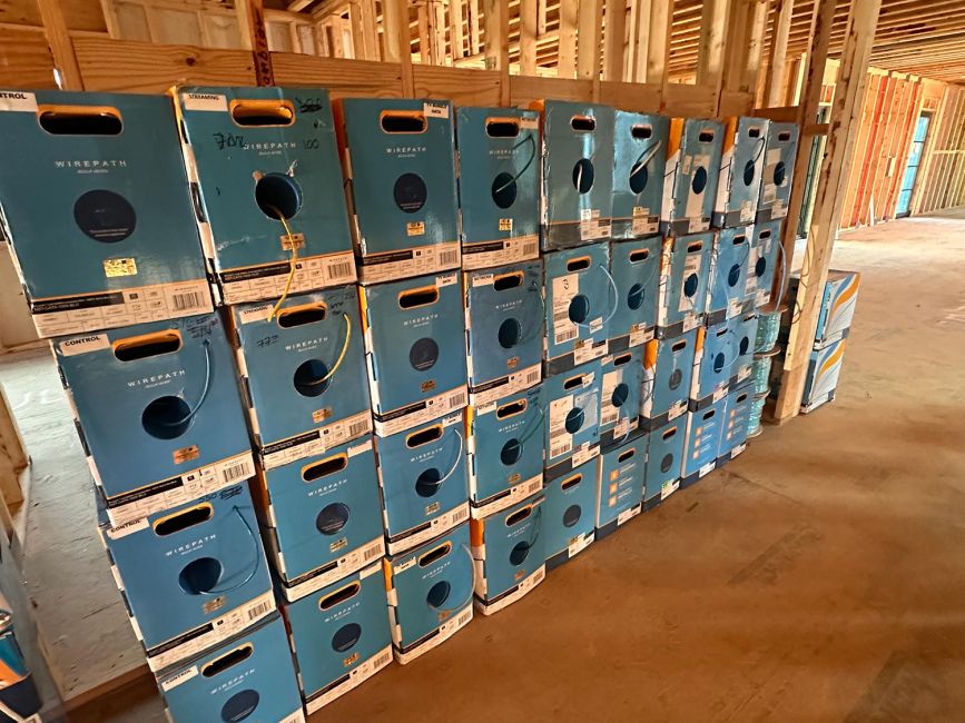 Stacked rows of blue cardboard wire dispenser boxes on a concrete floor under construction