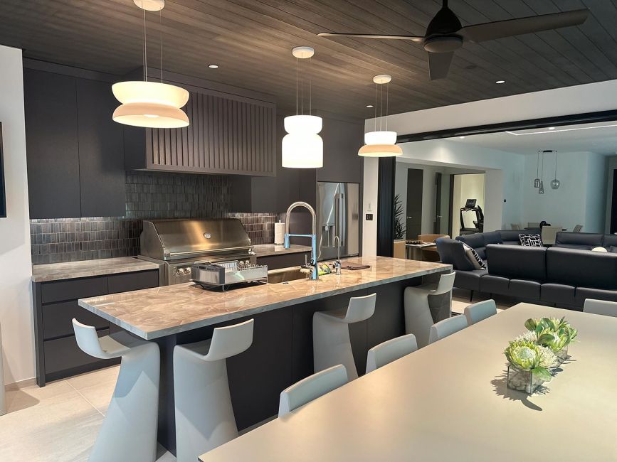Modern kitchen with marble island stools overlooking a spacious living room area