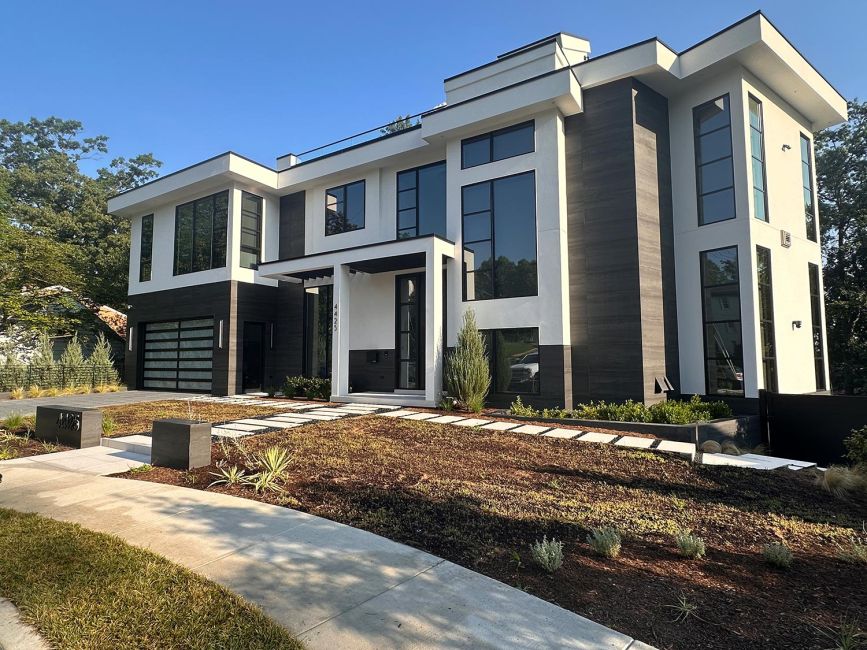 Three-story custom residential home facade with manicured landscaping and stone walkway